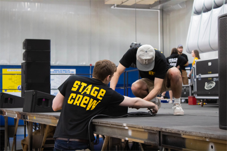 stage crew members hooking up sound speakers
