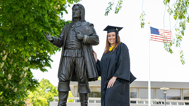 Student posing with Roger Williams statue