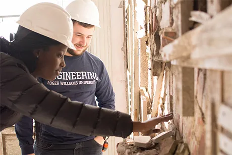 Engineering students examining a deteriorated wall.