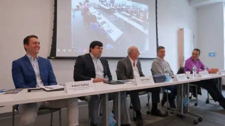 The five real-estate panelist sitting in the front of the room smiling.