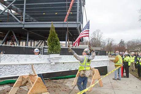 Construction crews prep the steel beam to be hoisted.