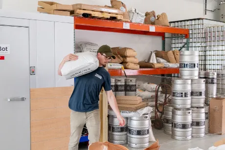 MacConnell carrying bag of malt across brewery.