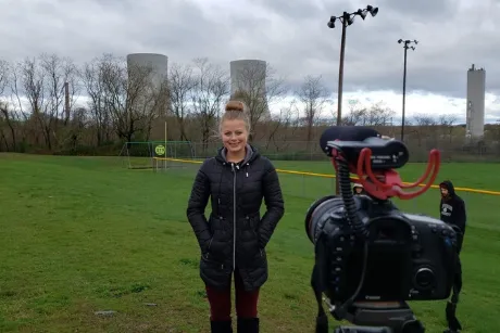 Person standing in grassy field looking at camera.