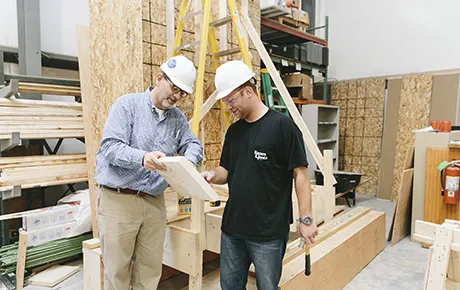 A student and professor work inside a construction lab.