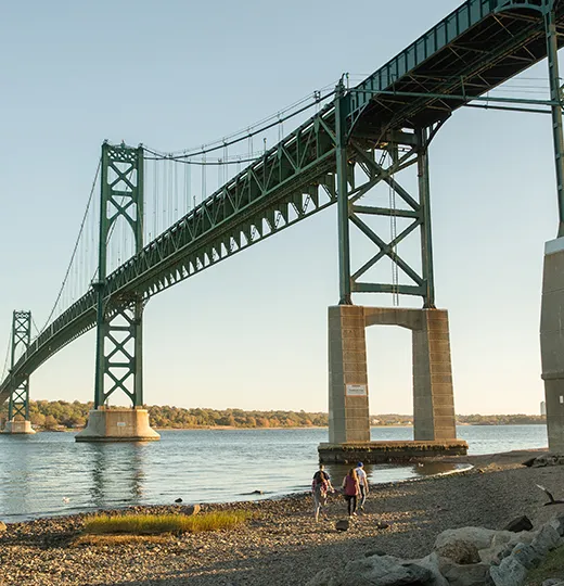 Students Walking on shoreline under bridge