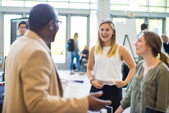 A Roger Williams University professor stands talking with two students