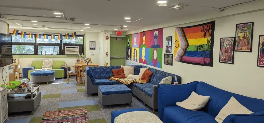 The QTRAC lounge area. Two large sofas, a tv and lots of LGBTQIA+ art.