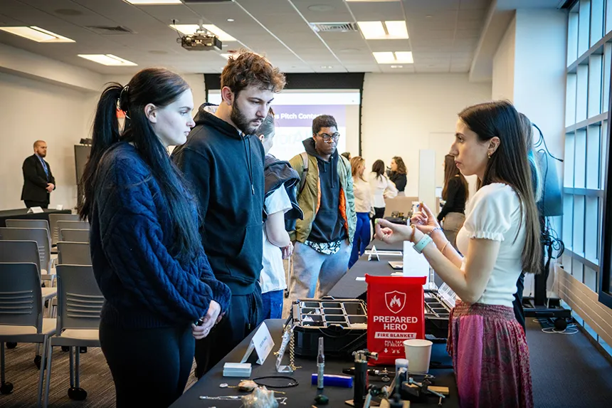 A student entrepreneur speaks to members of the RWU community at her table.