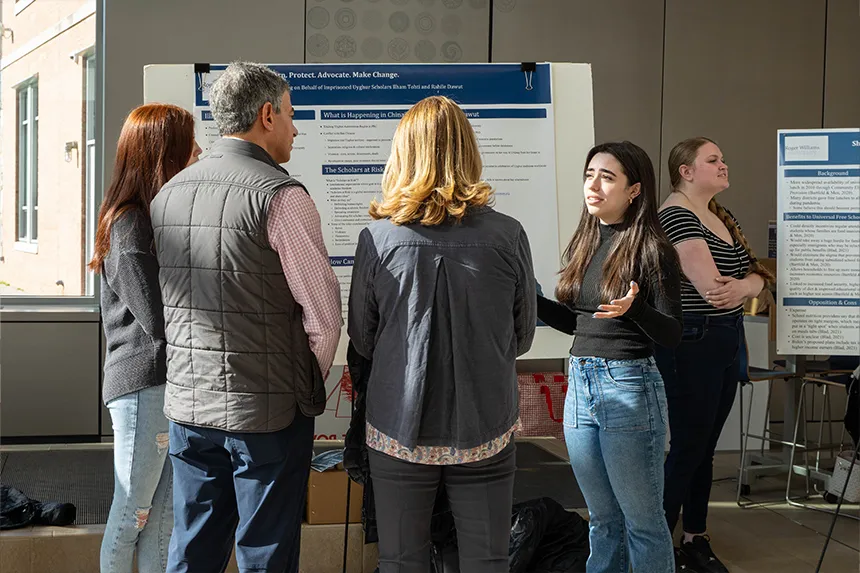 A student talking about her poster presentation to a group of people 
