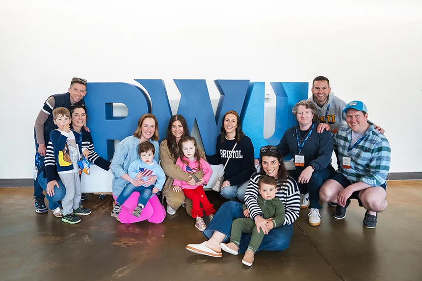 Families pose for a photo in front of RWU letters.