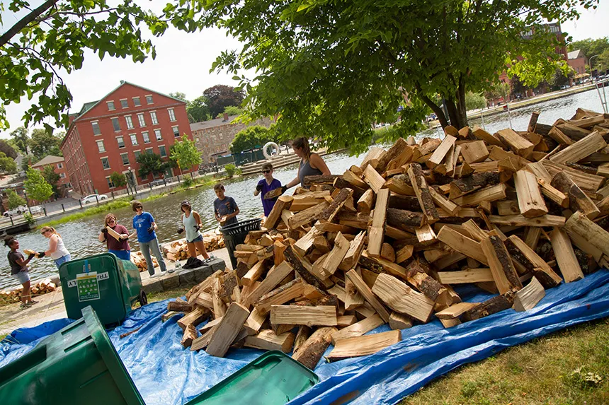 People taking wood from a massive pile.