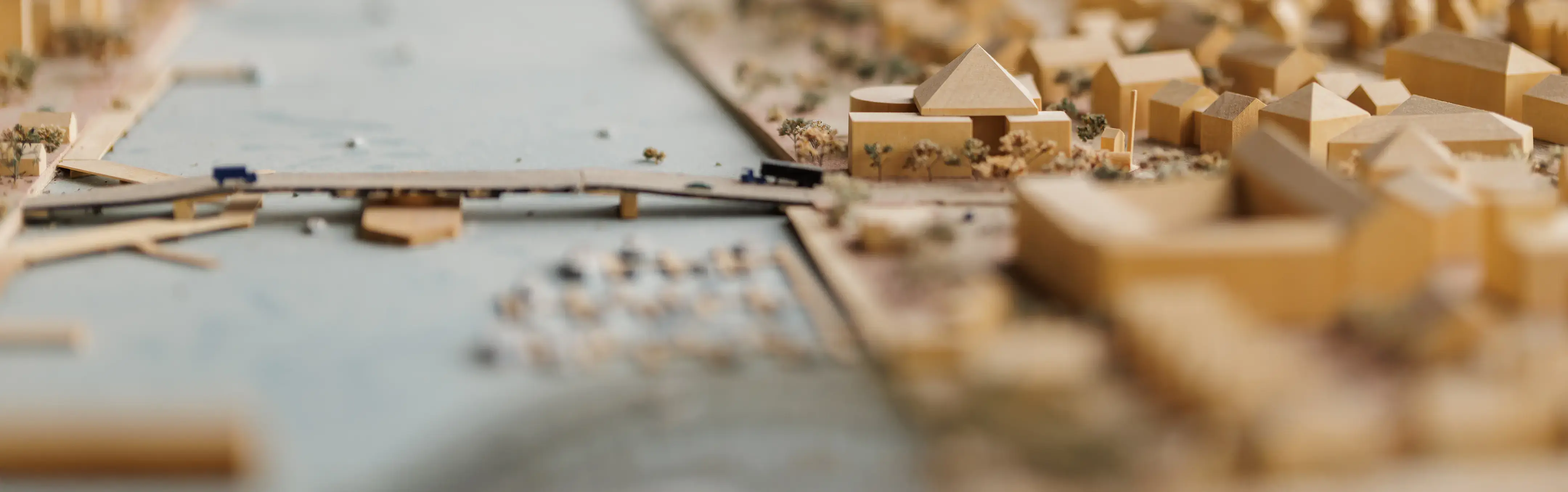 Close-up of a detailed architectural scale model showing buildings, roads, and a river through an urban landscape. 